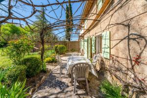 a patio with a table and chairs next to a building at La Tonnelle, clim, jardin in Malaucène
