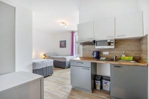 a kitchen with white cabinets and a bed in a room at Kleine Himmelpforte in Himmelpforten +6 photos