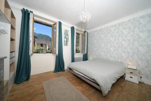 a bedroom with a bed with blue curtains and a window at Chambre Verte in Auzat