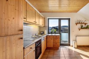 a kitchen with wooden cabinets and a large window at Vista-Homert in Eslohe