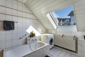 a bathroom with a tub and a washing machine at Vista-Homert in Eslohe +19 photos