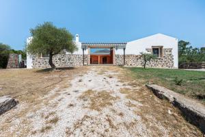 a house with a stone wall and a driveway at Villa Pedduzza in Orosei