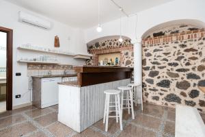 a kitchen with a stone wall and two bar stools at Villa Pedduzza in Orosei