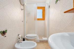 a white bathroom with a toilet and a sink at Casa Asfodeli in San Teodoro +15 photos