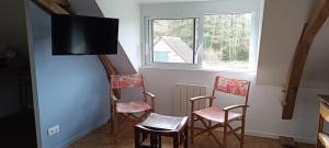 a room with four chairs and a tv on a wall at Chambres D'hôtes Les Préaux - in Cérans-Foulletourte