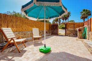 a green umbrella and two chairs on a patio at Casa Asfodeli in San Teodoro