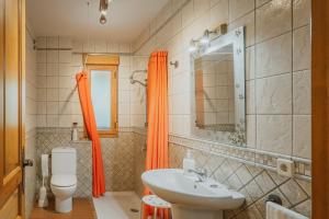 a bathroom with an orange shower curtain and a sink at Los Molinillos in Caballar +25 photos