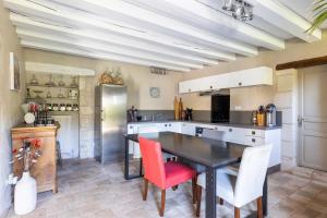 a kitchen with a black table and red chairs at Au Bo Voyage in Tavant +22 photos