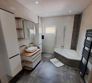 a bathroom with a tub and a sink and a bath tub at Ferienwohnung Paulus in Albstadt