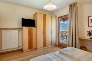 a bedroom with a bed and a tv and a window at Haus Rosengarten Apt C in Terlano