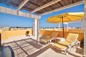 a patio with two chairs and an umbrella at Royal Cabanas Golf 87 in Cabanas de Tavira