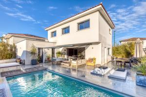a villa with a swimming pool in front of a house at Sublime Maison Moderne avec piscine in Mauguio