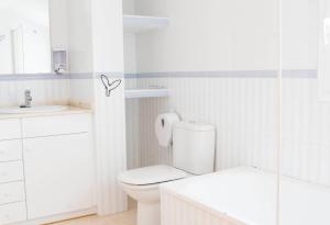 a white bathroom with a toilet and a sink at Constance in L'Ampolla