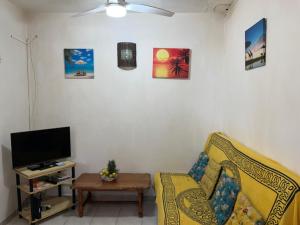 a living room with a couch and a tv at Chez sidoine Meublé 1 chambre in Le Moule