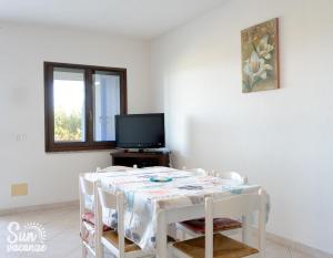 a white room with a table with chairs and a tv at Villa Malamuri in Budoni