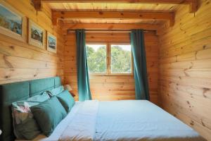 a bed in a log cabin with a window at Chalet Pondok Indah in Plouégat-Moysan +15 photos