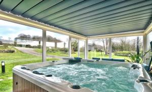 a hot tub in a room with a large window at Chalet Pondok Indah in Plouégat-Moysan
