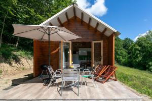 a wooden deck with a table and chairs and an umbrella at Chalet Pondok Indah in Plouégat-Moysan