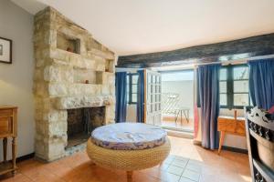 a living room with a stone fireplace and a stool at Le Grimaldi in Cagnes-sur-Mer