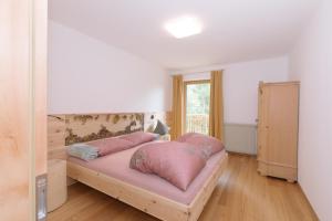 a bedroom with a bed with pink pillows on it at Ferienwohnung Berg Wieserhof in Aldino