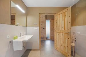 a bathroom with a sink and a wooden door at Pitschlhof Apt Zirbe in Aldino