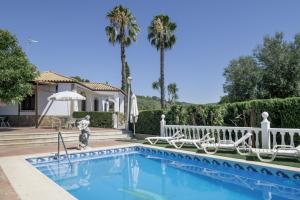 a villa with a swimming pool and palm trees at Finca Arroyuelo in Prado del Rey