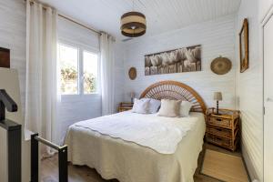 a bedroom with a bed with white sheets and a window at Villa Cap Ferret - Réf 230 in Lège-Cap-Ferret