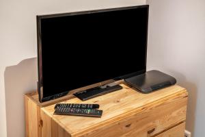 a television on a wooden stand with two remote controls at Fewo Kleines Glück in Friesenheim
