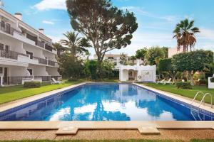 a swimming pool in front of a building at Mouramar Vilamoura in Vilamoura
