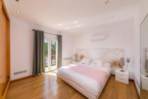 a white bedroom with a large bed and a window at Villa Costa Eugenia in Cala d´Or +33 photos
