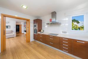 a large kitchen with wooden cabinets and a window at Villa Costa Eugenia in Cala d´Or