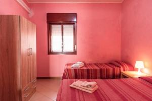 a pink room with two beds and a window at Appartamento A - Le Terrazze in Ribera