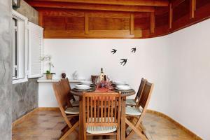 a dining room with a table with chairs and birds on the wall at Casa Cordel in Playa Honda