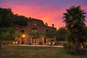 an old stone house with a palm tree at sunset at Masia Sa Calma - La Tribu in Susqueda