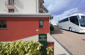 un bus blanc est garé à côté d'un bâtiment dans l'établissement Hotel Brindor, à Poirino