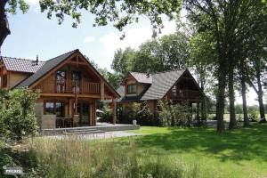 a log house with a porch and a yard at Houten villa Tine in Den Ham