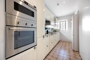 a kitchen with white cabinets and stainless steel appliances at Liberal Wing Villa in Portimão