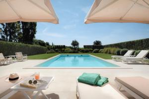 a swimming pool with chairs and an umbrella at Liberal Wing Villa in Portimão