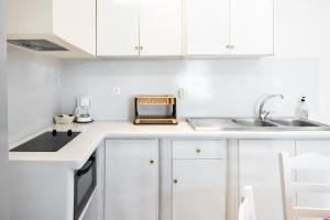 a white kitchen with white cabinets and a sink at Elysium in Glinádhon +17 photos