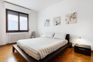 a white bedroom with a large bed and a window at Palma’s house in Dongo