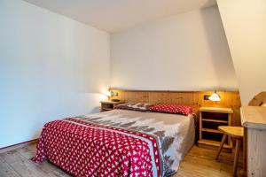 a bedroom with a bed with a red and white blanket at Giongo Residence Aparthotel 101 in Lavarone