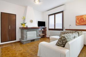 a living room with a white couch and a fireplace at Palma’s house in Dongo