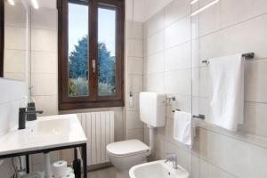a bathroom with a toilet and a sink and a window at Palma’s house in Dongo