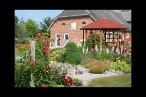 a garden in front of a house with a gazebo at Ferienhaus Nanny Und Helene in Uphusum