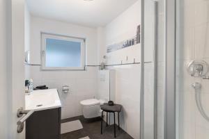 a white bathroom with a toilet and a sink at Haus No 6 in Lahr +29 photos