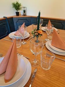 a wooden table with plates and wine glasses and napkins at Ferienwohnung Sonnenschein in Nagel