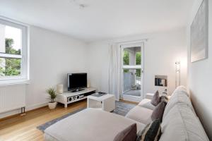 a white living room with a couch and a tv at Haus No 6 in Lahr