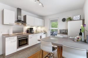 a kitchen with white cabinets and a table with chairs at Haus No 6 in Lahr