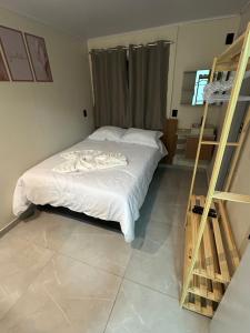 a bedroom with a bed with white sheets and a ladder at Castilhos Hotel in Barracão