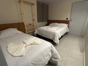 a hotel room with two beds with white sheets at Castilhos Hotel in Barracão +2 photos